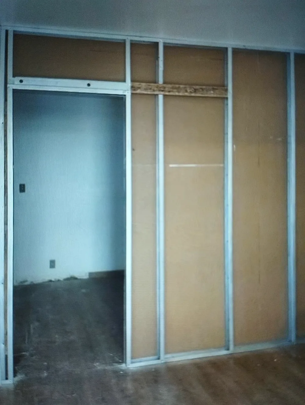 Estrutura de drywall com o vão da porta já definido e uma das faces fechada.