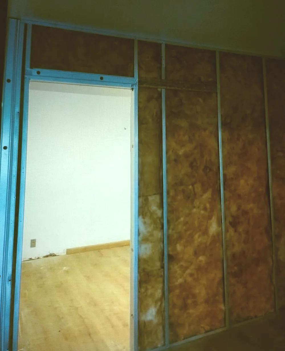 Lã mineral instalada entre os montantes metálicos, antes de fechar o segundo lado da parede de drywall.