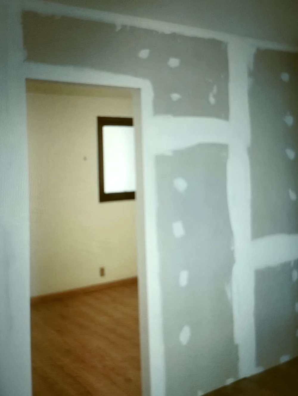 Parede de drywall fechada com massa aplicada nas emendas entre chapas e sobre as cabeças dos parafusos.