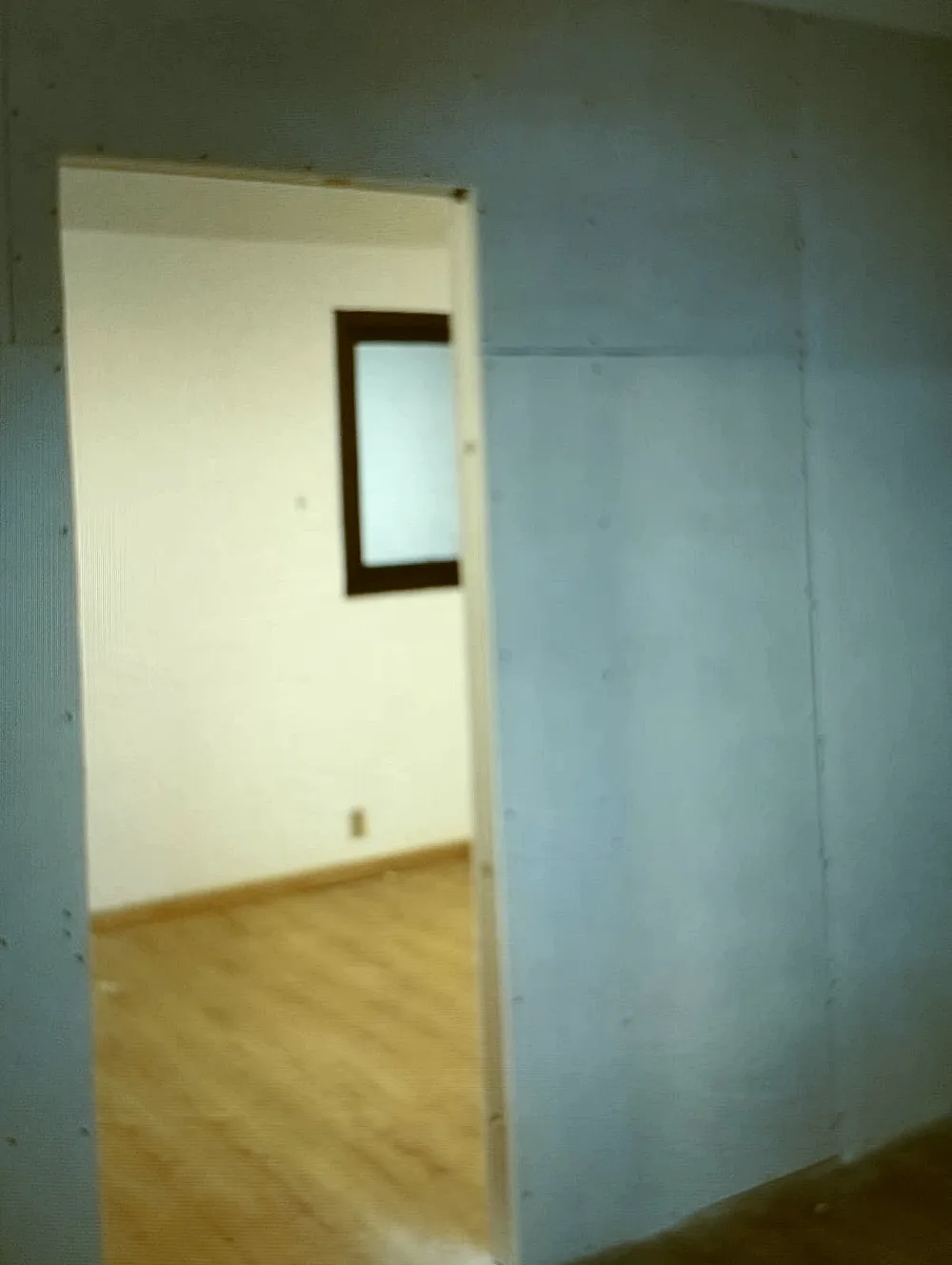 Parede de drywall pronta, lisa e fechada, com o vão de passagem para o outro ambiente.